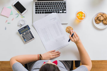 woman-with-tax-report-eating-cookie-at-office-P5CG24V-1536x1024-1